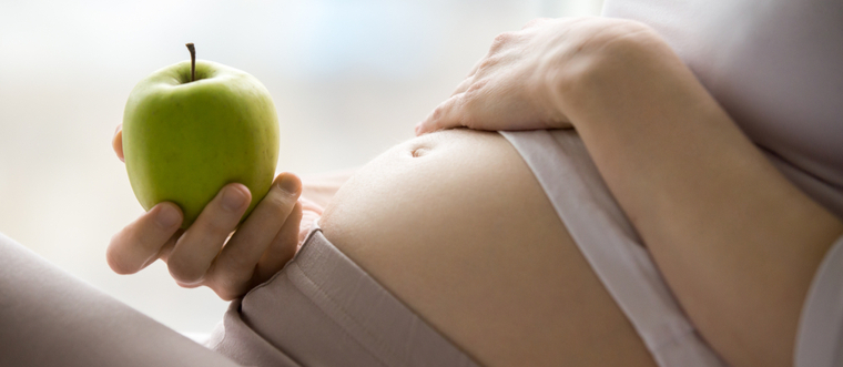 Pregnant woman holding a green apple